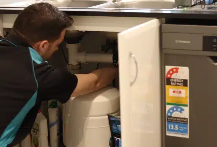 Hot water system plumbing A hot water plumber installing a hot water hose and valve a sink