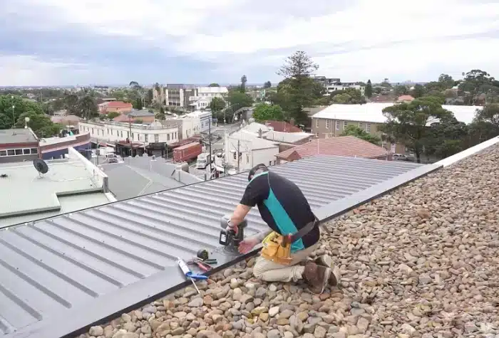A roof plumber drilling a gutter as part of their roof plumbing services